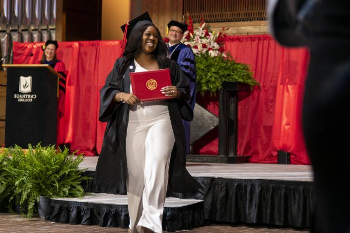 A 2023 博彩网址大全 graduate beams as she leaves the Commencement stage after receiving her d...